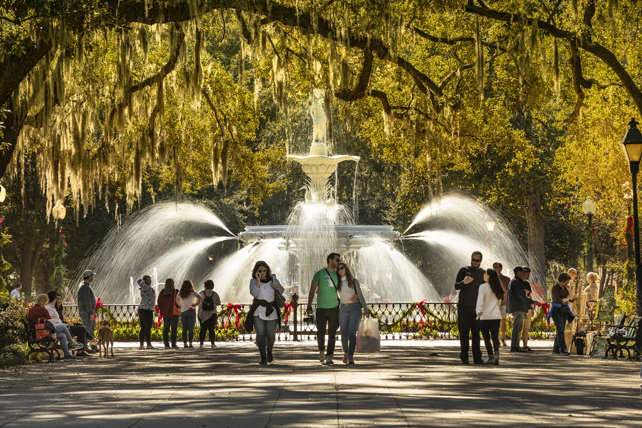 People walk by the historic fountain along the foot paths and trees of Forsyth Park.